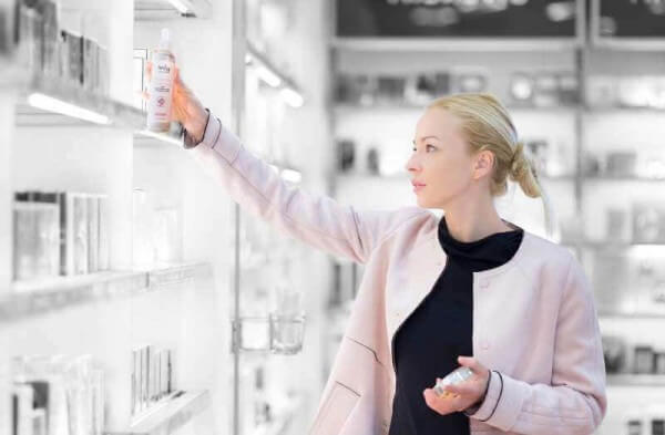 female buying rosewater off store shelf