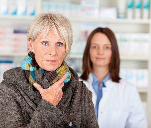 woman in coat with pharmacist in background in store