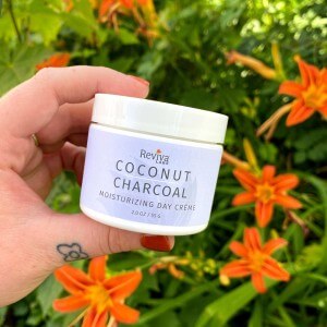 coconut charcoal day cream jar in hand