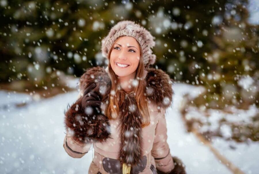 Wintertime Walk - woman walking in snow with hat, gloves, smiling