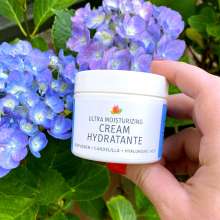 Cream Hydratante being held in front of flowers