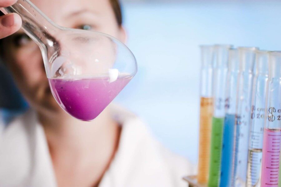 Woman review flask of chemicals with test tube vials