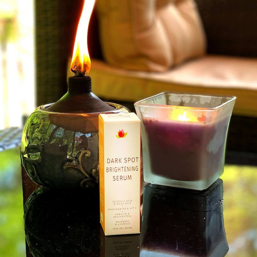 dark spot brightening serum on table in front of candle