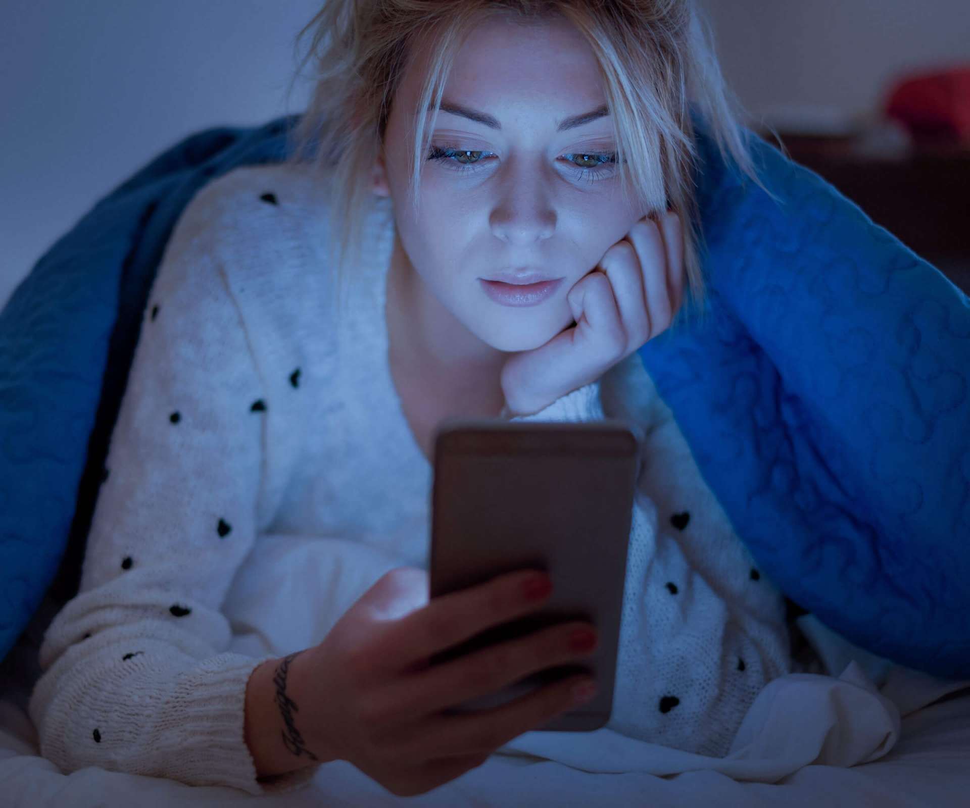 girl looking at phone in bed