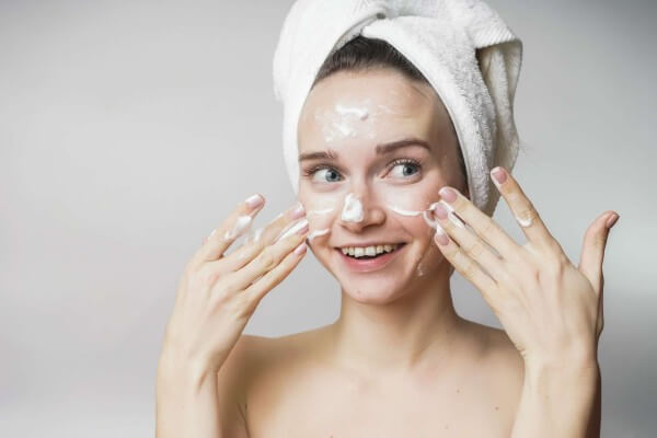 funny woman in a towel on the head happy cleanses the skin with vaseline cream