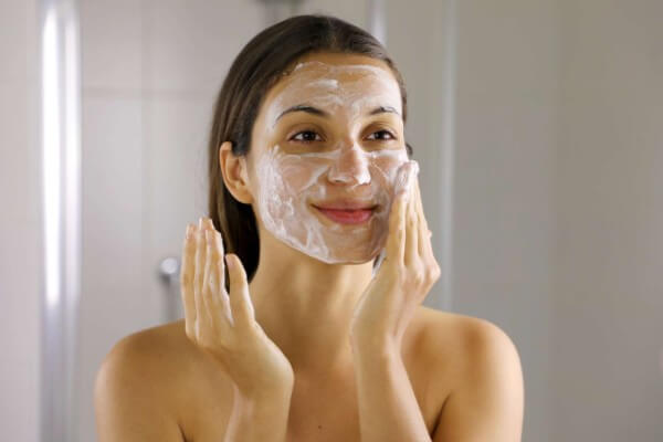 Face wash exfoliation scrub soap woman washing scrubbing with skincare cleansing product.