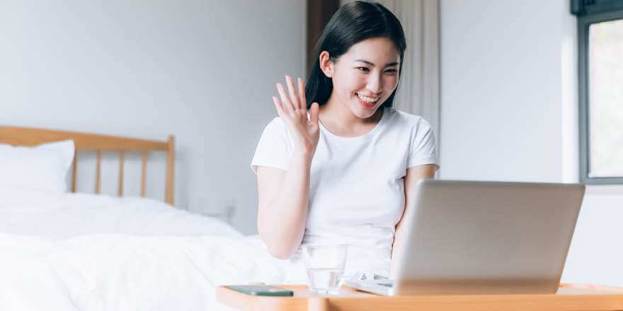 asian woman waving during video chat