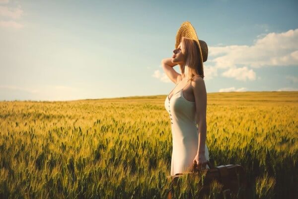 blonde-woman-in-hat-with-suitcase-in-wheat-field