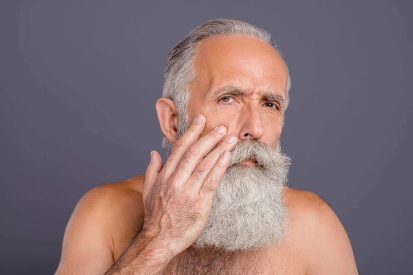 Older Male gentlemen inspecting face for skincare needs