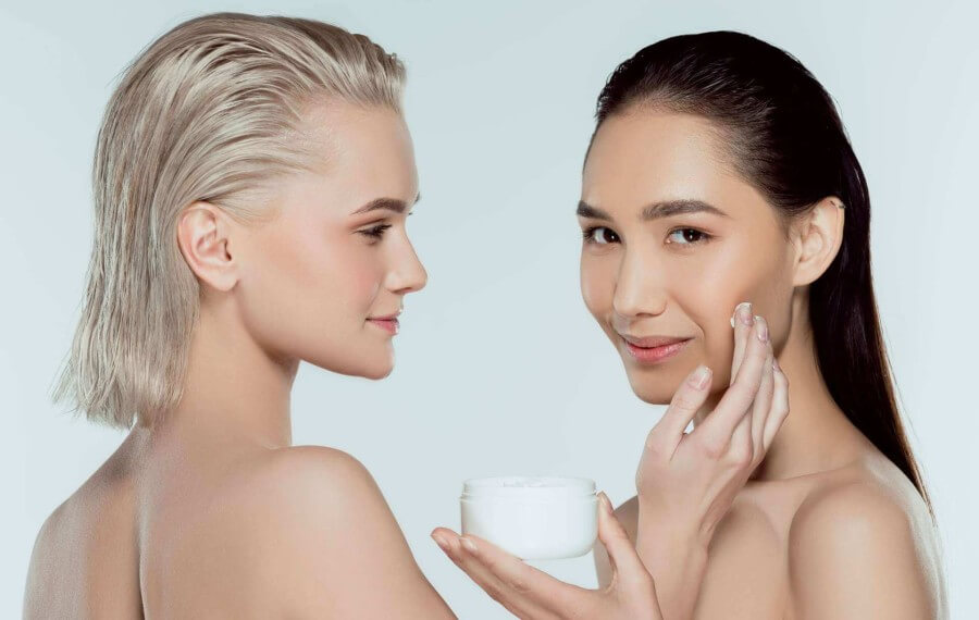 two women applying skin care during photo shoot