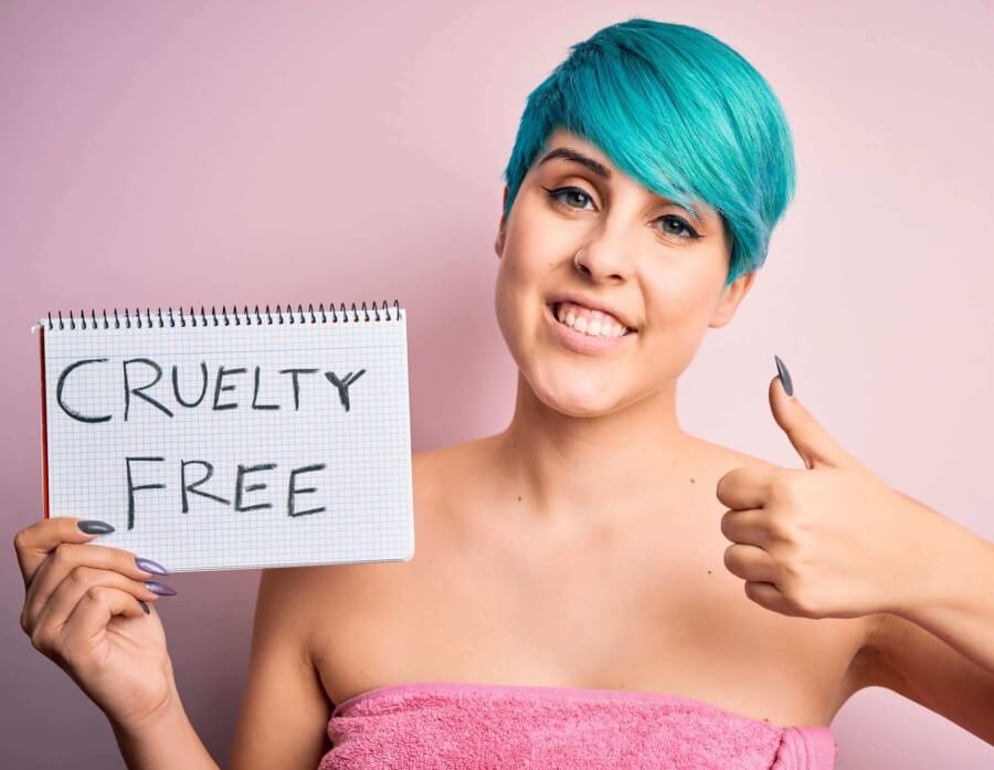 Female with blue hair giving thumbs up and holding cruelty free sign