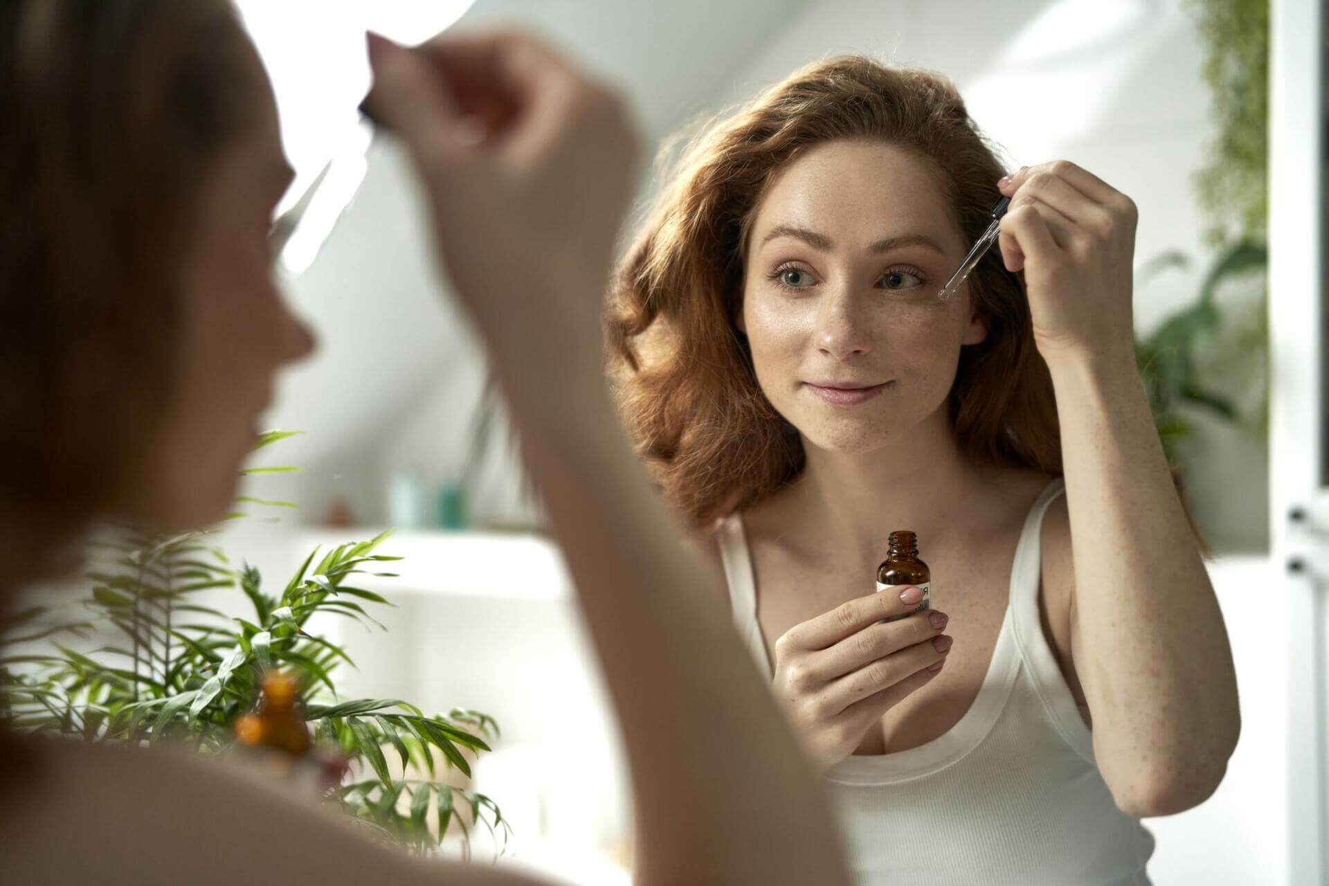 woman using serum to face in the bathroom