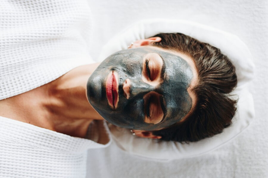 woman relaxing with a charcoal facial mask