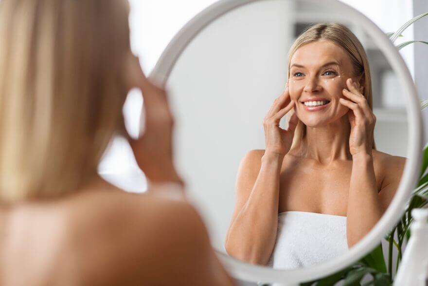 anti aging cosmetics. beautiful middle aged woman applying eye cream at home