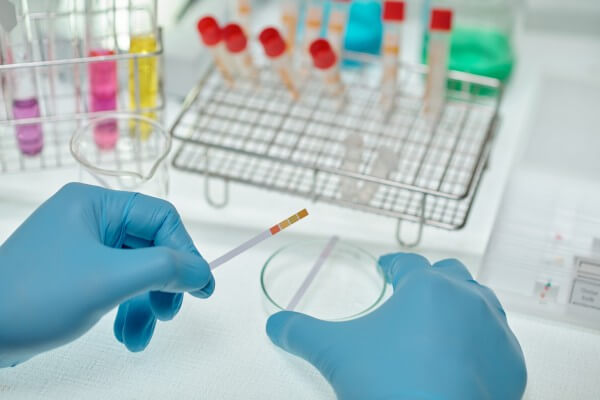 close up of gloved hands of chemist holding paper indicator of ph acid