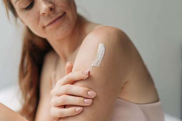 young woman uses body skin care cream. treat and beauty procedure.