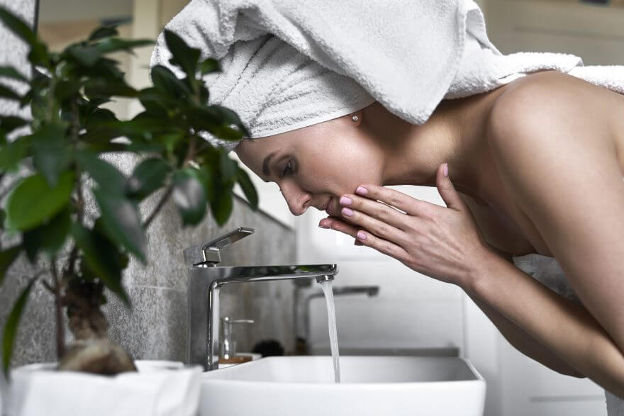 side view of woman washing face with water in the bathroom