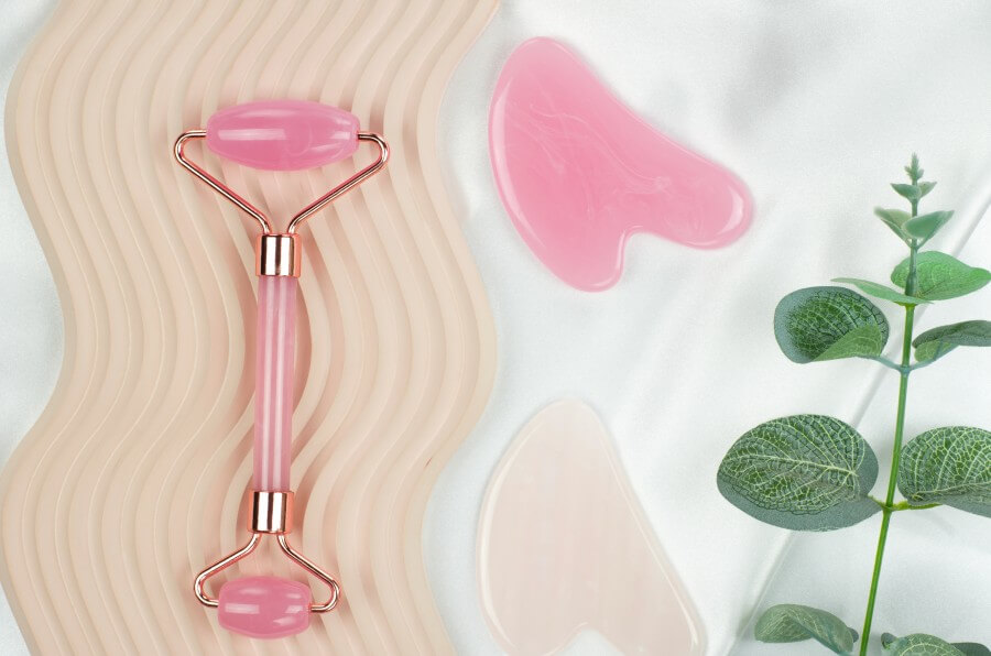 jade facial massager and gua sha massage scraper on wave podium. facial skin care products