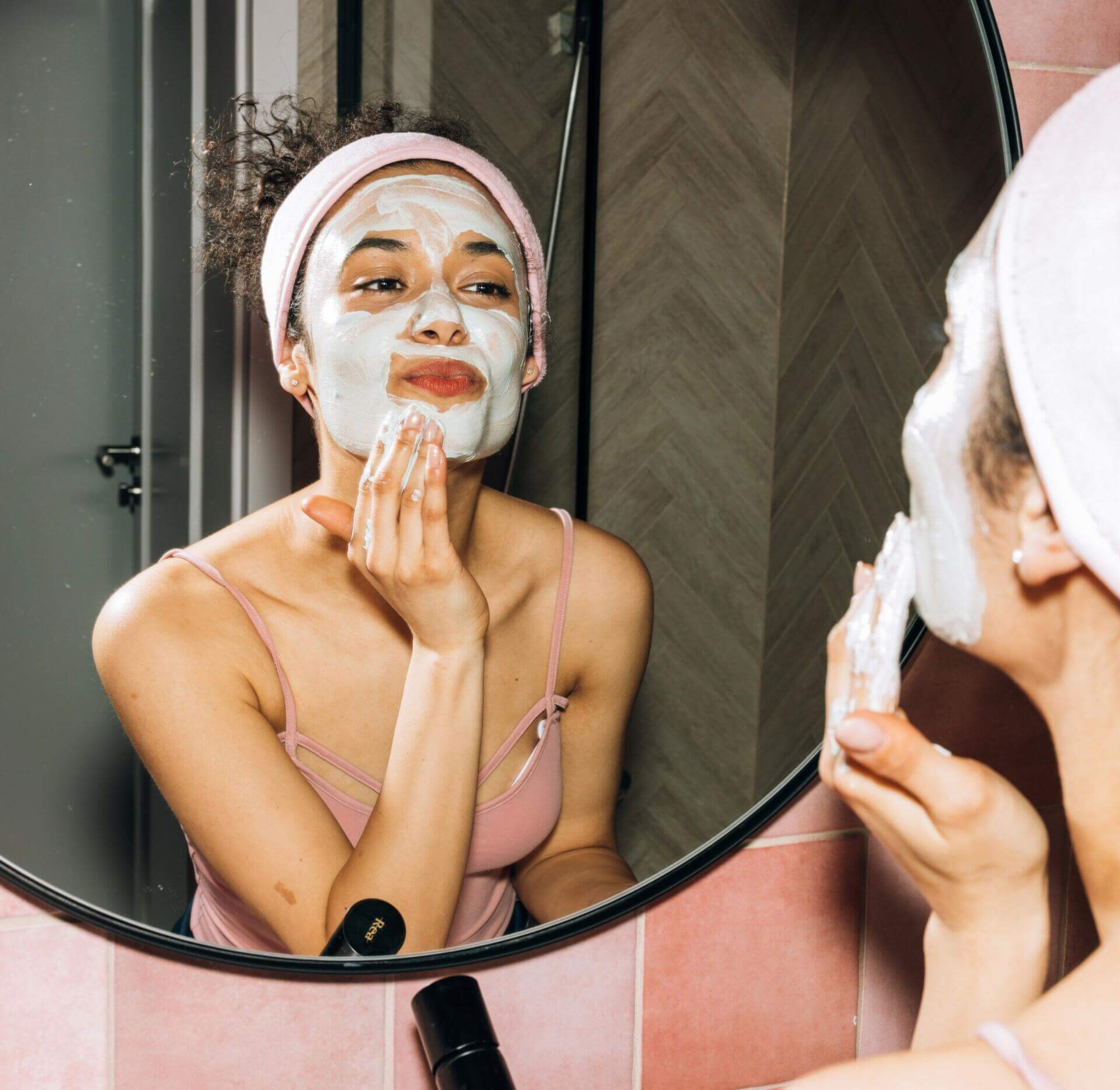 woman applying cream to face as seen in mirror 7143283