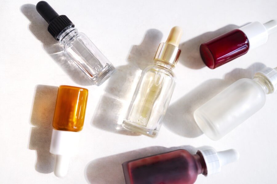 serum with collagen and peptides in colorful glass bottles on li