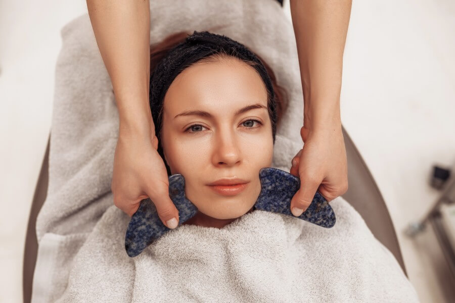 woman receiving facial massage in beauty salon.