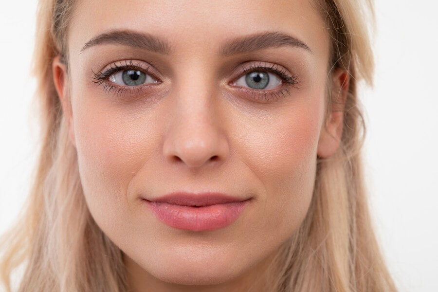 close up portrait of a blonde of european appearance on a white background looking at the camera with a slight smile on her face