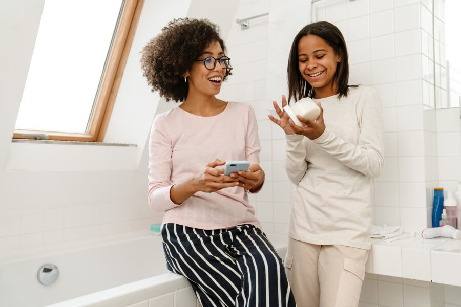 happy african american woman and daughter doing skincare in bathroom