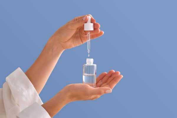 serum with a pipette in female hands on a blue background.