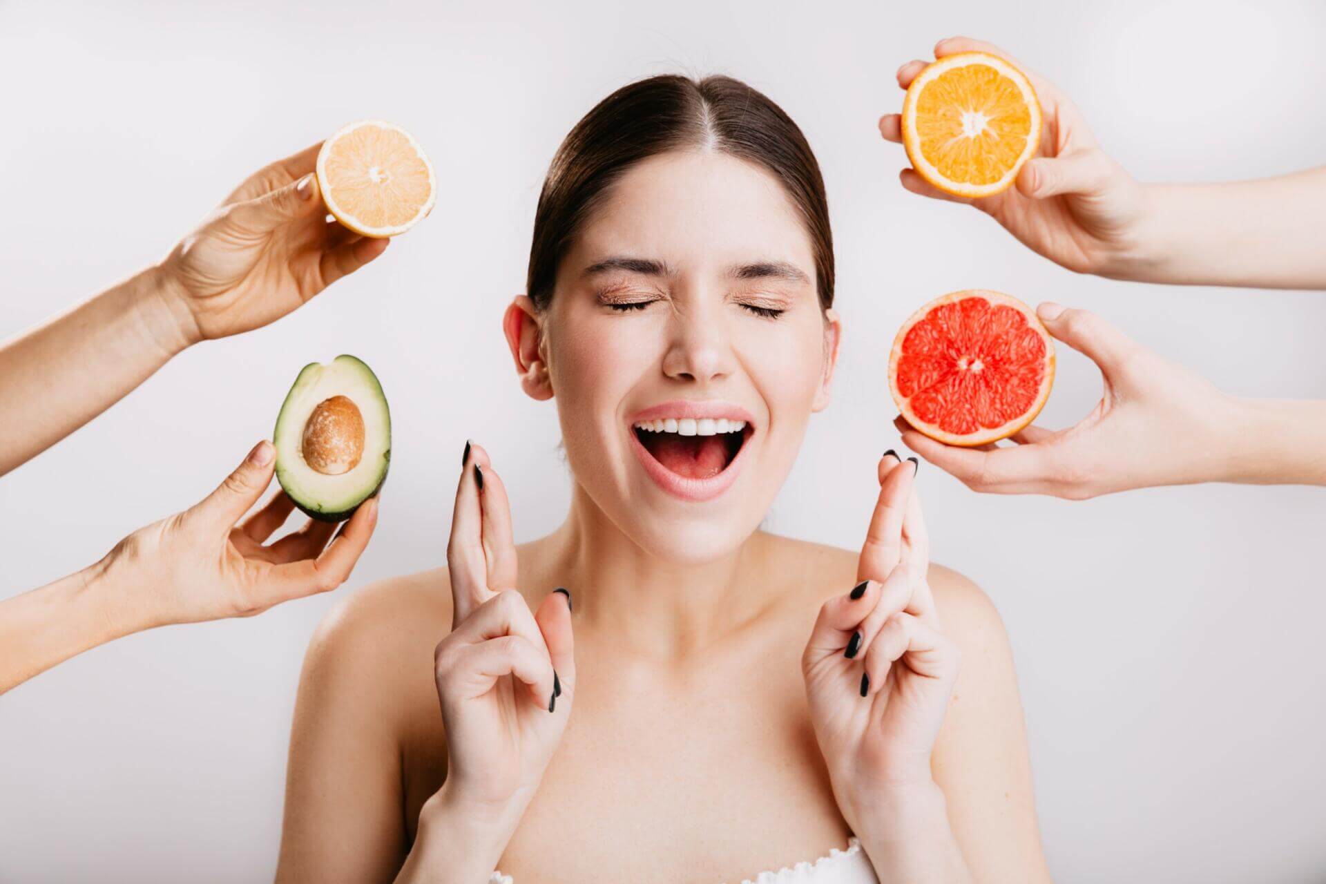 joyful girl makes wish. portrait of model without makeup on white background with fruits