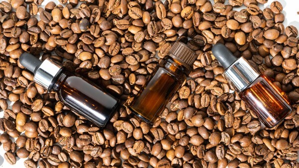 organic oil. cosmetic oil, facial and body skin care product with coffee extract. a glass bubble next to the coffee beans. coffee essential oil. selective focus.