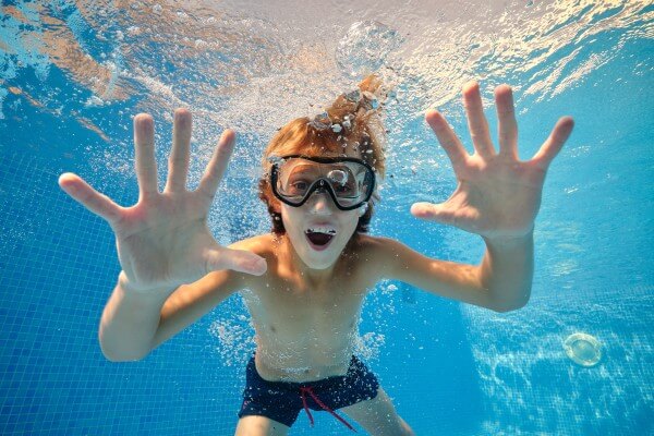 excited boy showing palms in swimming pool