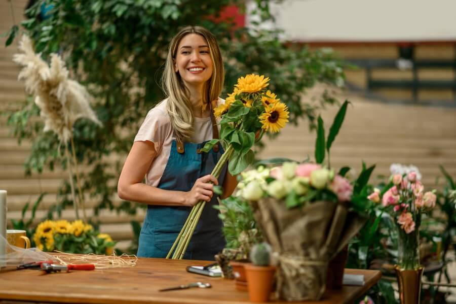 florist standing and holding bouquet of sunflowers in flower sho