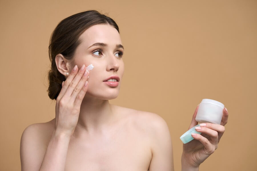 antiage treatment. beautiful caucasian young woman applying moisturizing cream on face. skin care