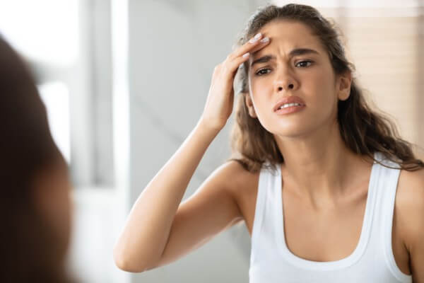 concerned woman searching wrinkles looking at forehead in bathroom indoor