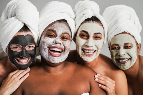 multigenerational women having fun wearing face beauty mask for skin care therapy main focus on african girl face