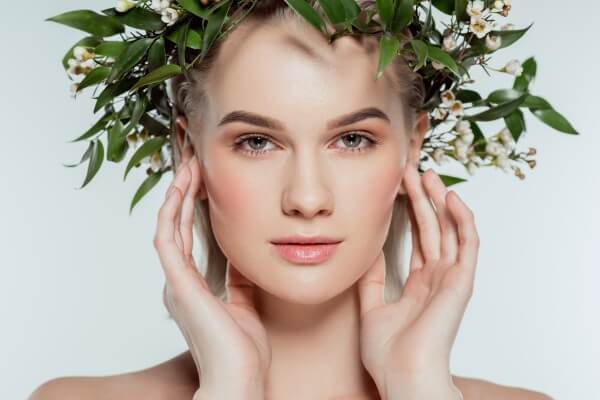 portrait of blonde girl in floral wreath, isolated on grey