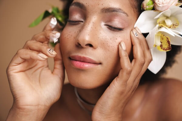 portrait of young freckled african american woman applying facia