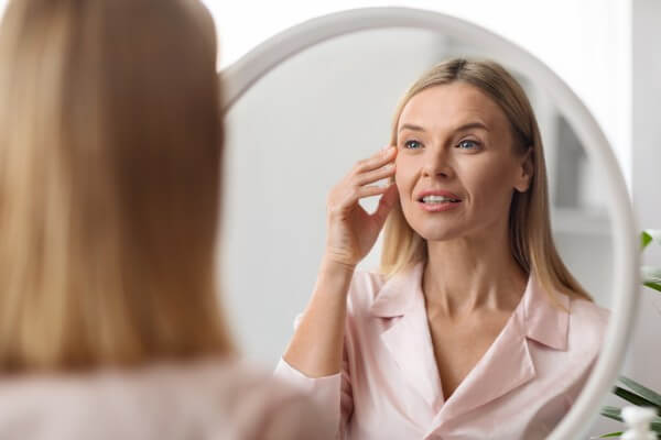 closeup shot of middle aged beautiful woman looking in mirror at home