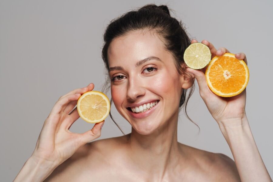 smiling half naked woman posing with citruses on camera