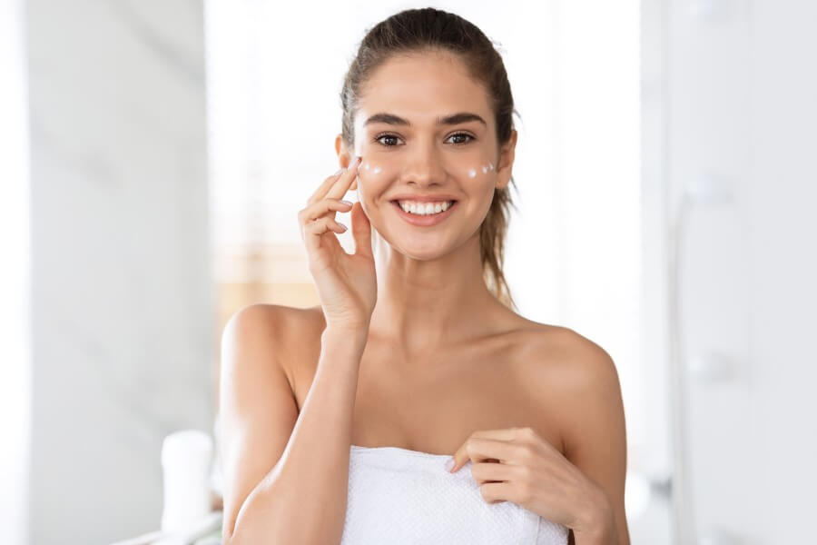 woman applying patches under eyes moisturizing skin posing in bathroom