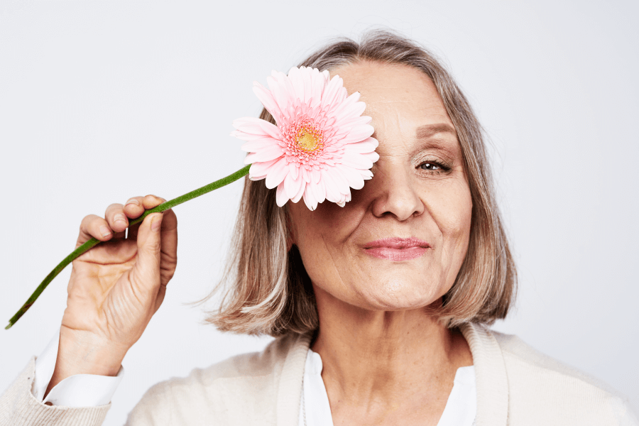 menopausal woman holding flower in front of her eye 279254512