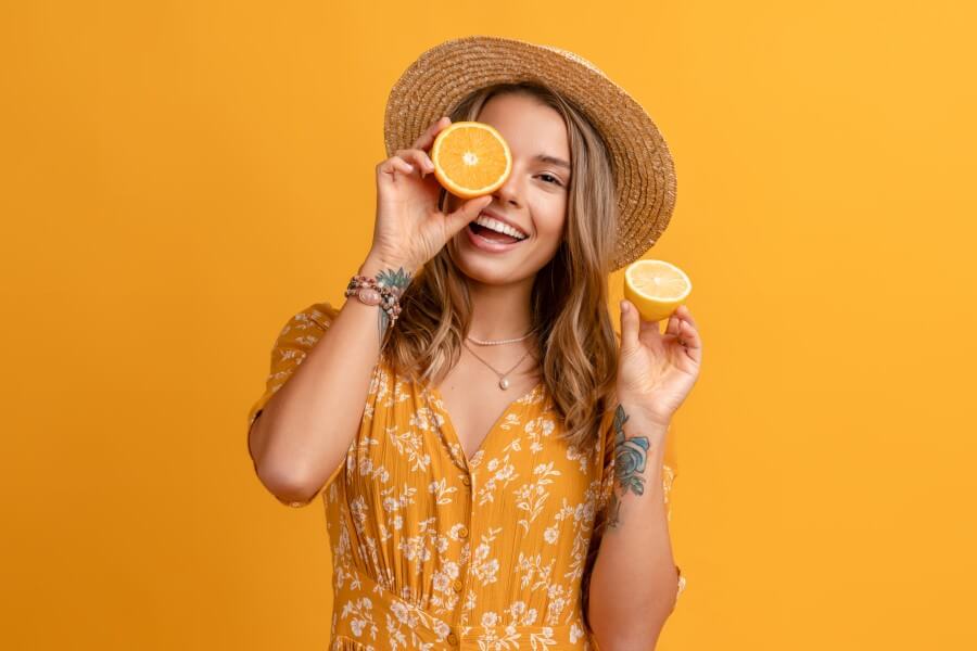 beautiful attractive stylish woman in yellow dress and straw hat holding lemons