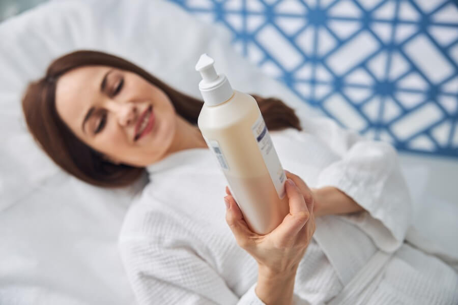 charming woman holding bottle of cosmetic cream