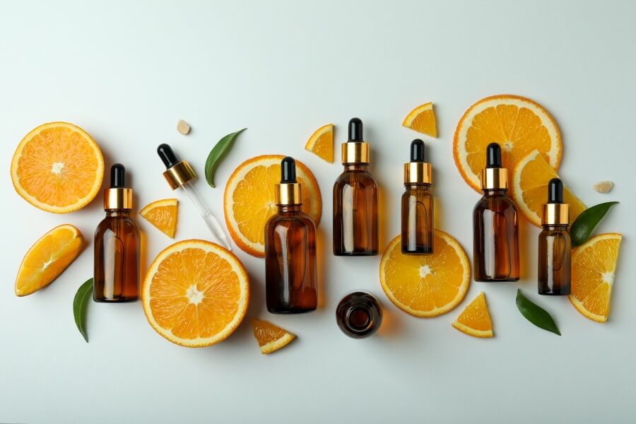 dropper bottles with oil and orange slices on white background