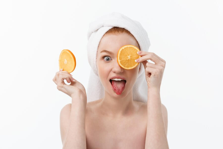 great food for a healthy lifestyle. beautiful young shirtless woman holding piece of orange standing against white background.