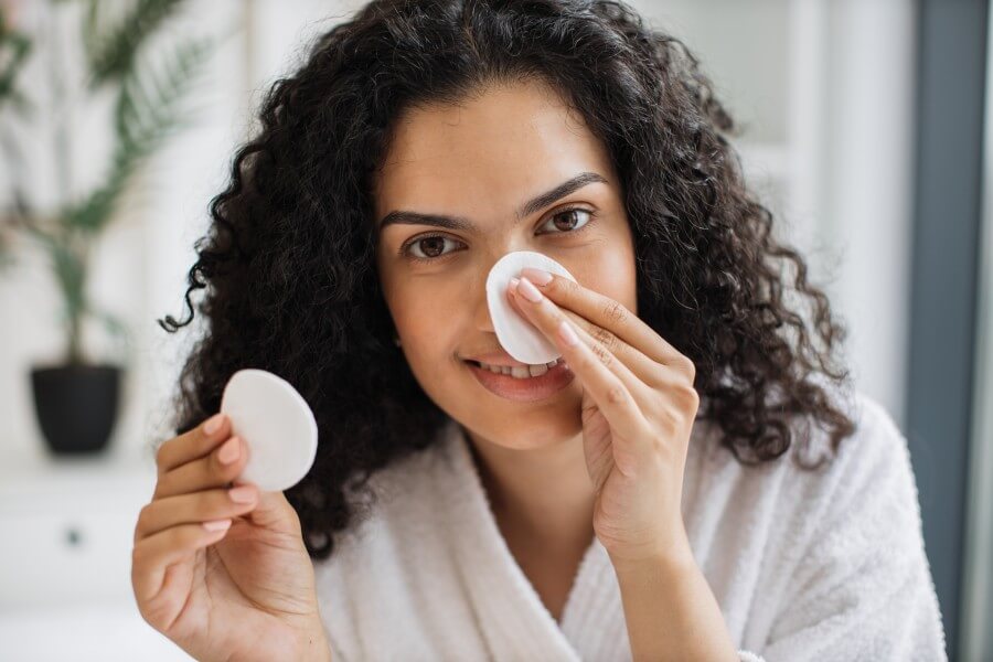 multiracial woman removing cosmetics from nose area