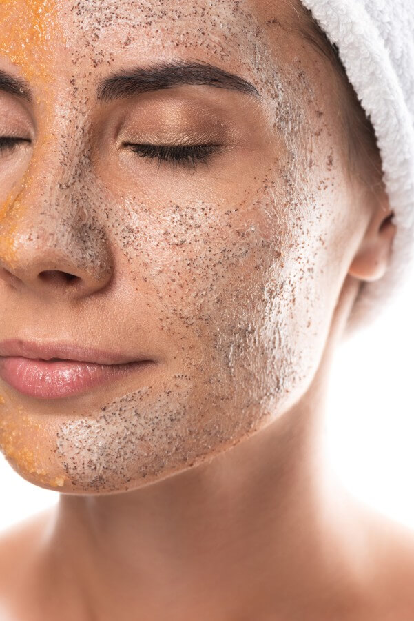 partial view of young woman with scrub on face with closed eyes isolated on white