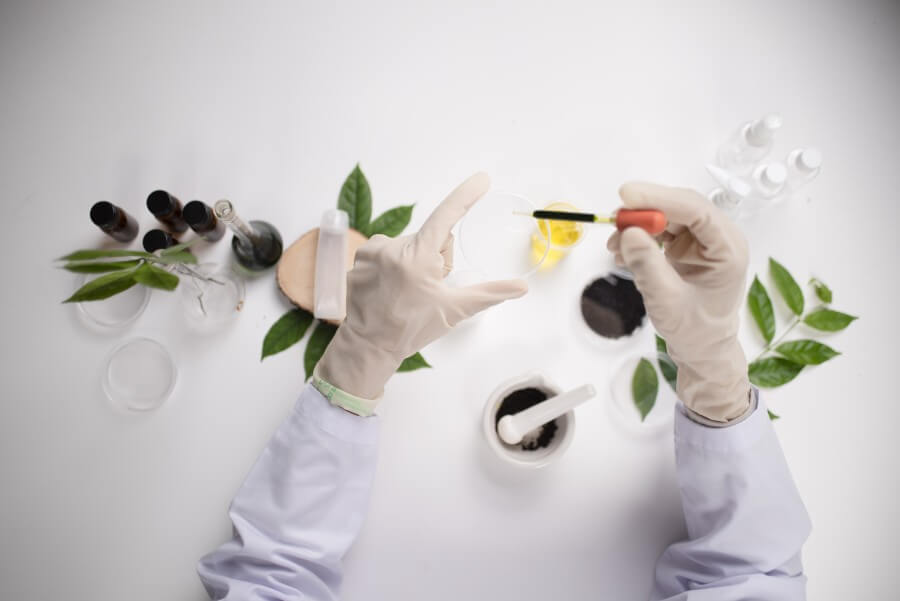 scientist hand holding green leaf in glass cuvette on laboratory. biotechnology concept.