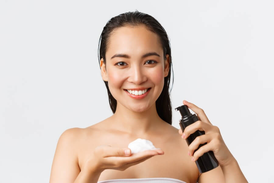 skincare, women beauty, hygiene and personal care concept. close up of beautiful smiling asian woman standing naked, using face cleanser, washing off makeup, treating acne prone skin