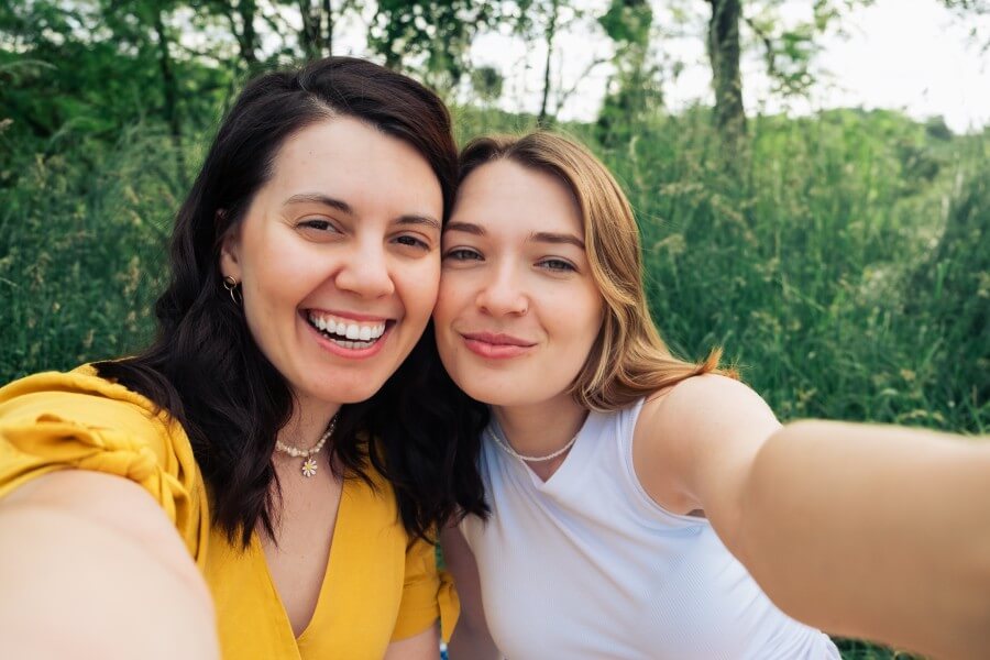 smiling couple of women taking selfie at a picnic on a summer day